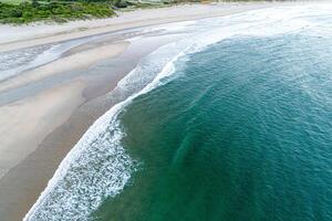 summer vacation destination empty beach with clear ocean waves and green vegetation aerial drone view photo