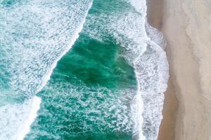 top down drone photography breaking surf on a wide beach with people Aerial image from a drone photo