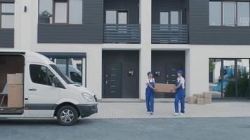 Two young workers of removal company are loading boxes and furniture into a minibus 14 video