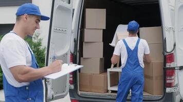 Two young workers of removal company are loading boxes and furniture into a minibus 50 video