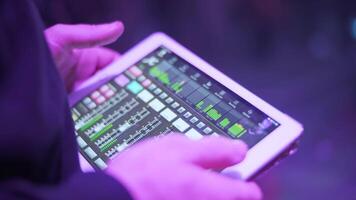 Sound engineer at the concert adjusts the sound on the tablet video