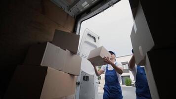 Two young workers of removal company are loading boxes and furniture into a minibus 65 video