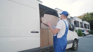 Two young workers of removal company are loading boxes and furniture into a minibus 27 video