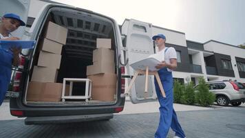 Two young workers of removal company are loading boxes and furniture into a minibus 55 video