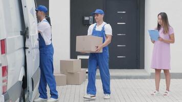 Two young workers of removal company are loading boxes and furniture into a minibus 4 video