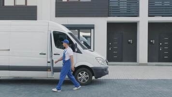 Two young workers of removal company unload boxes and furniture from minibus into customer's home video