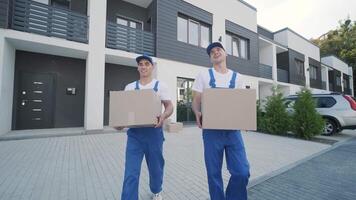 Two young workers of removal company are loading boxes and furniture into a minibus 25 video