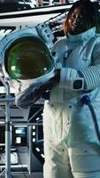 Vertical Astronaut suit helmet and laptop inside spaceship control bay displaying diagnostics and mission telemetry. Cosmonaut equipment next to notebook in space station showing performance metrics video