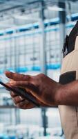 Smart factory expert using digital device app to test automated systems and ensure reliability. Worker uses tablet to identify bottlenecks and optimize gear based on sensors data, camera A close up video