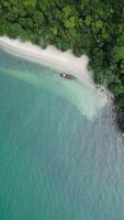 Vertical Aerial view of motorboat speeding in tropical waters near Thai island, thrilling summer adventure featuring boat creating white waves with scenic blue waters and exotic shoreline views. video
