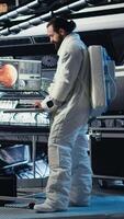 Vertical Astronaut putting helmet on before stepping out for scheduled operations outside space station, doing fist bump with colleague. Cosmonaut preparing to leave starship after landing on planet, camera A video