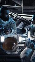 Vertical Team of astronauts checking human expansion in space mission logs on green screen laptop. Cosmonauts using chroma key notebook during mankind survival expedition, camera A video
