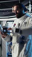 Vertical Cosmonaut using tablet in spaceship conducting safety checks during mankind survival expedition. Astronauts monitoring life support systems during human expansion in space mission, camera A video
