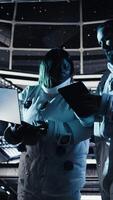 Vertical Team of astronauts running data analysis on laptop before stepping out outside space station. Teamworking cosmonaut verifying mission parameters on notebook after landing on planet, camera A video