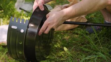Men assemble a safe mini grill for cooking steaks without risking grass fires in the outdoor area. video