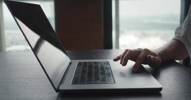 Successful businessman sitting at desk working at laptop in office. Business person using touch pad laptop computer in front of window at office video