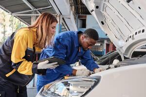 EV car check, mechanic workers, diverse coworker inspects and service of engine and battery in fixed automobile garage station, professional technology transportation industry business. photo
