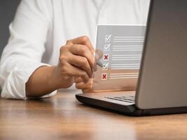 Businessman is making a checkmark and a cross symbol on a document management system or DMS on a virtual screen photo
