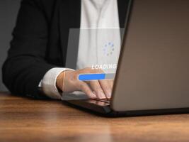 Businessman in a suit uses a laptop for loading and processing data on a virtual screen photo
