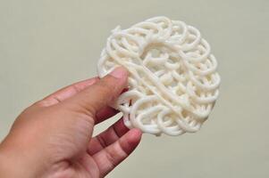 Hand Holding a Round White Indonesian Rice Cracker photo