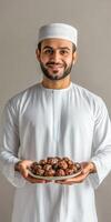 Arab young man holding plate of dates photo