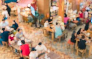 Abstract blurred top view of crowded cafeteria or food court with people seating at tables background photo
