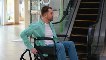 Man in wheelchair looking at escalator in shopping mall video
