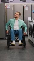 Customer in wheelchair choosing home appliances in electronics store video