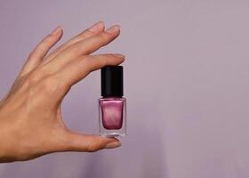 Pink violet nail polish in a woman's hand close up. Background banner with copy space for text photo
