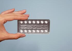 A blister of pills in a woman's hand close up. Background banner with copy space for text photo