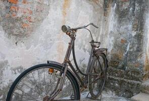 a black vintage bicycle parked in the corner of an old building photo