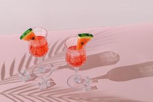 Summer scene with refreshing watermelon drink and palm tree leaves shadow on pink and white background. Sun and shadows. Minimal cocktail concept. Trendy summertime party idea. Summer aesthetic. photo