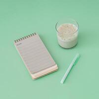 To do list in spiral notepad with iced matcha latte. Trendy pastel green background. photo