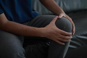 a man sitting on a couch with his knee in pain photo