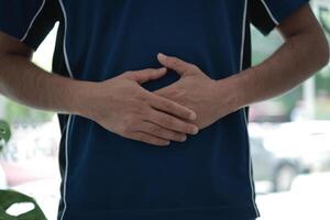 a man hand holding his stomach in pain photo