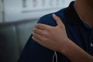 a man is holding his arm up to his shoulder, shoulders pain photo
