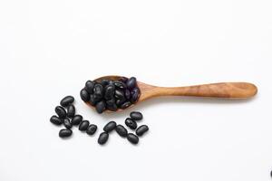 Black beans in spoon on white background. photo