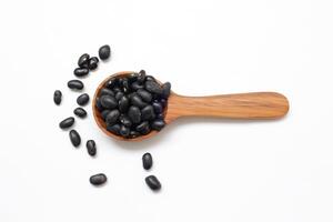 black beans on wooden spoon on a white background photo