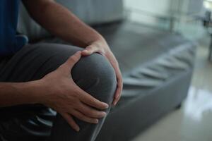 a man with knee pain sitting on a couch photo