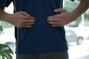 a man is holding his stomach while wearing a blue shirt photo