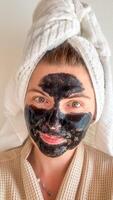 A woman of Caucasian descent in a waffle robe and charcoal mask, embracing Hygge serenity and National Relaxation Day photo