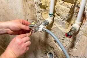 Hands of a Caucasian male twist pipes amid vintage stonework, evoking Fix It Fair energy and National Plumbers Day ingenuity photo