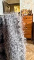 A fuzzy gray shawl drapes over a vintage chair, invoking Slavic winter solace and the enigmatic spirit of Maslenitsa photo