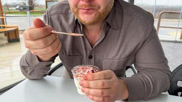 A jovial Caucasian man savors strawberry parfait amidst the rustic tranquility, echoing Pancake Days indulgence and Hygge coziness photo