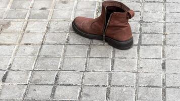 Lonely leather boot on cobblestone whispers wanderlust tales, evoking lost and found themes and celebrating International Left Handers Day photo