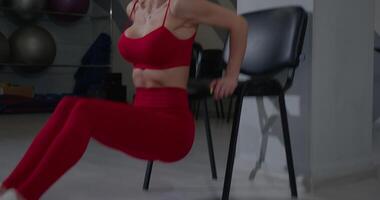 Fitness enthusiast performs reverse chair pushups in a gym setting focusing on triceps strength and overall fitness routine video
