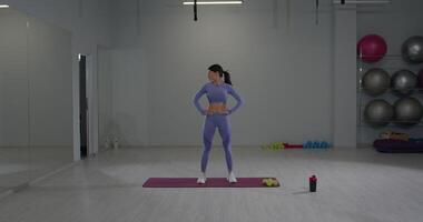 Athletic girl performs head movements for stretching and warm up exercises in a modern gym setting video