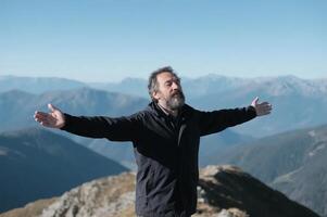 A man with his arms outstretched on top of a mountain photo