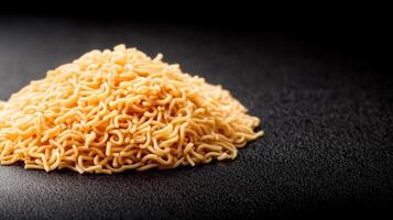 Close-up of uncooked dry instant ramen noodles on black surface with detailed texture and golden color, emphasizing food preparation and snack ingredients photo