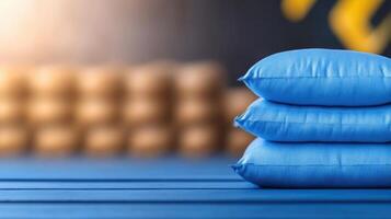 Close-up of blue cushions stacked on a wooden surface with a blurred background of wooden logs or blocks for interior decor or home furnishings photo